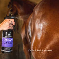 Image Bild: Detail-Nahaufnahme zeigt das Dream Coat Fellglanz Spray mit zielgenauem Sprühnebel während der Anwendung an einem braunen Pferd, Hintergrund dezent verschwommene Stallung.