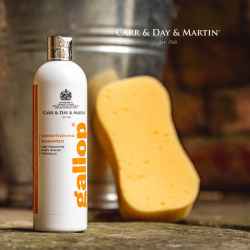 Image Bild: weiße Gallop Pflege Shampoo Produktflasche 500 ml mit orangefarbener Aufschrift steht auf dem Stallboden vor einem Blecheimer mit Schwamm.
